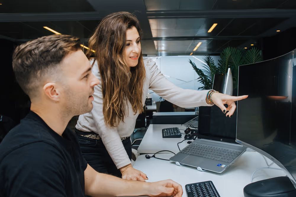 An employee pointing at another employee's screen